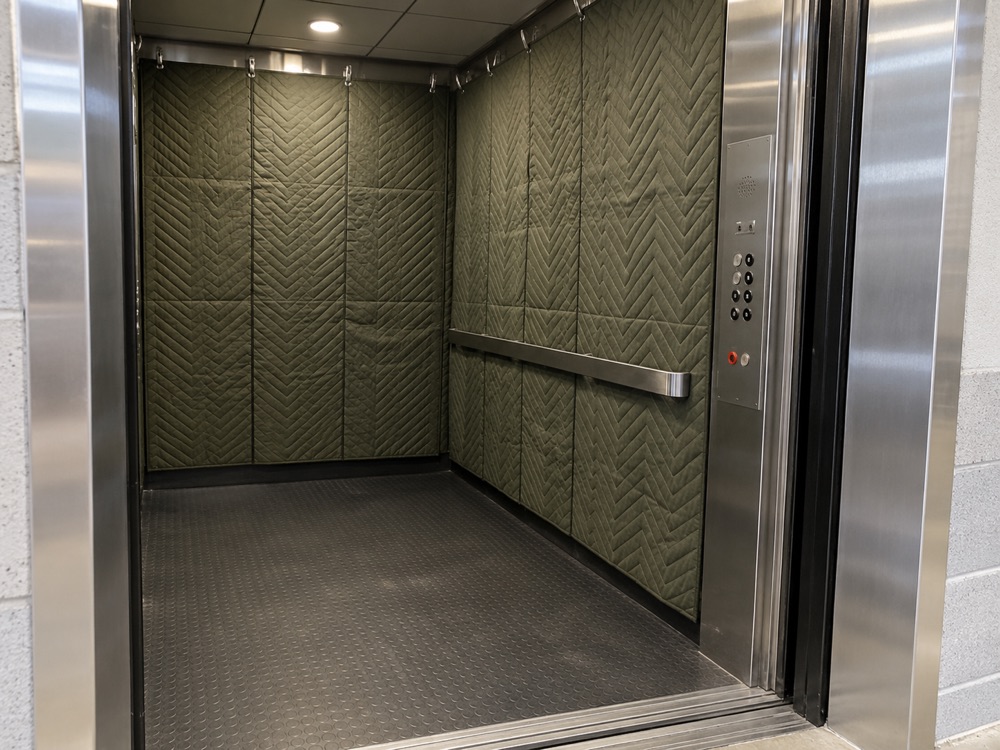 Olive quilted protection pads fitted inside a service elevator